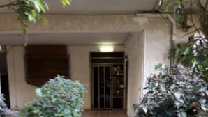 Un camino empedrado que lleva a la entrada de un edificio con puerta de vidrio.