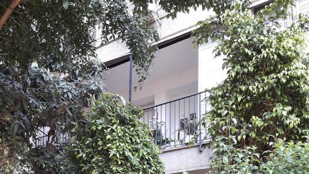 Un patio con abundante follaje, un camino empedrado y un edificio con balcones.