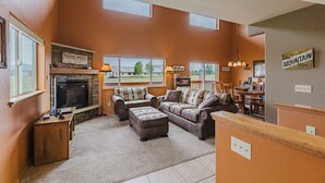 Una sala de estar con chimenea, televisor y comedor con sillas y mesa.