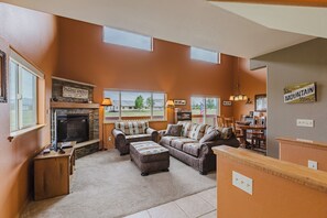 A living room with a fireplace, a television, and a dining area with chairs and a table.
