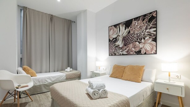 A hotel room with two beds, a large floral artwork on the wall, and a modern chair. - A (VA013.2 ) TH Ayuntamiento 2D (Valencia / València)