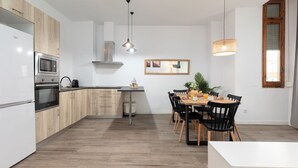 A modern kitchen with wooden cabinets, a built-in oven, and a dining area with a table and chairs. - A (VA013.2 ) TH Ayuntamiento 2D (Valencia / València)