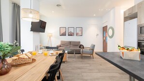 A modern kitchen with a dining area, a sofa, and a TV mounted on the wall. - A (VA013.2 ) TH Ayuntamiento 2D (Valencia / València)