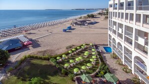 A hotel with multiple balconies, a pool, and a beach area with umbrellas and sun loungers. - Hotel Viand (Sunny Beach)