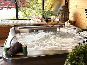 Un bain à remous avec vue sur un jardin et une statue de Bouddha.