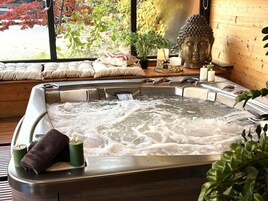 Un jacuzzi con vistas a un jardín y una estatua de Buda.