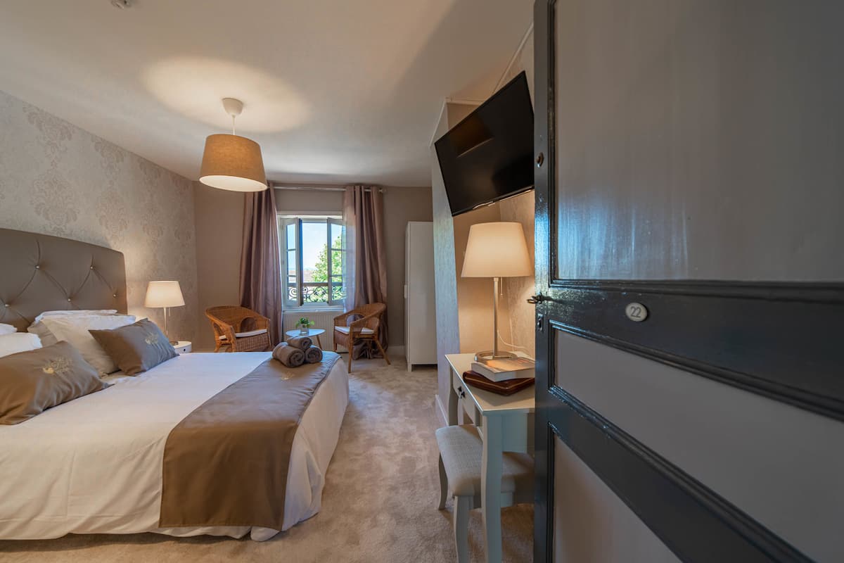 Une chambre d’hôtel avec un grand lit, un bureau avec une lampe, une chaise et un téléviseur.