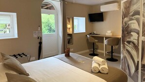 A hotel room with a bed, a desk, a chair, a TV, and a window.
