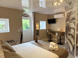 Una habitación de hotel con cama, escritorio, silla, televisor y ventana.