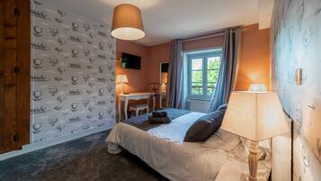Un dormitorio con cama, mesita de noche, lámpara y ventana con cortinas.