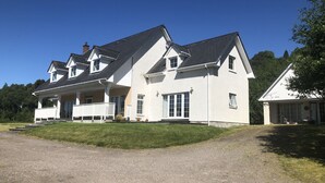 Ein großes, zweistöckiges Haus mit einer überdachten Veranda und einer Schotterauffahrt.