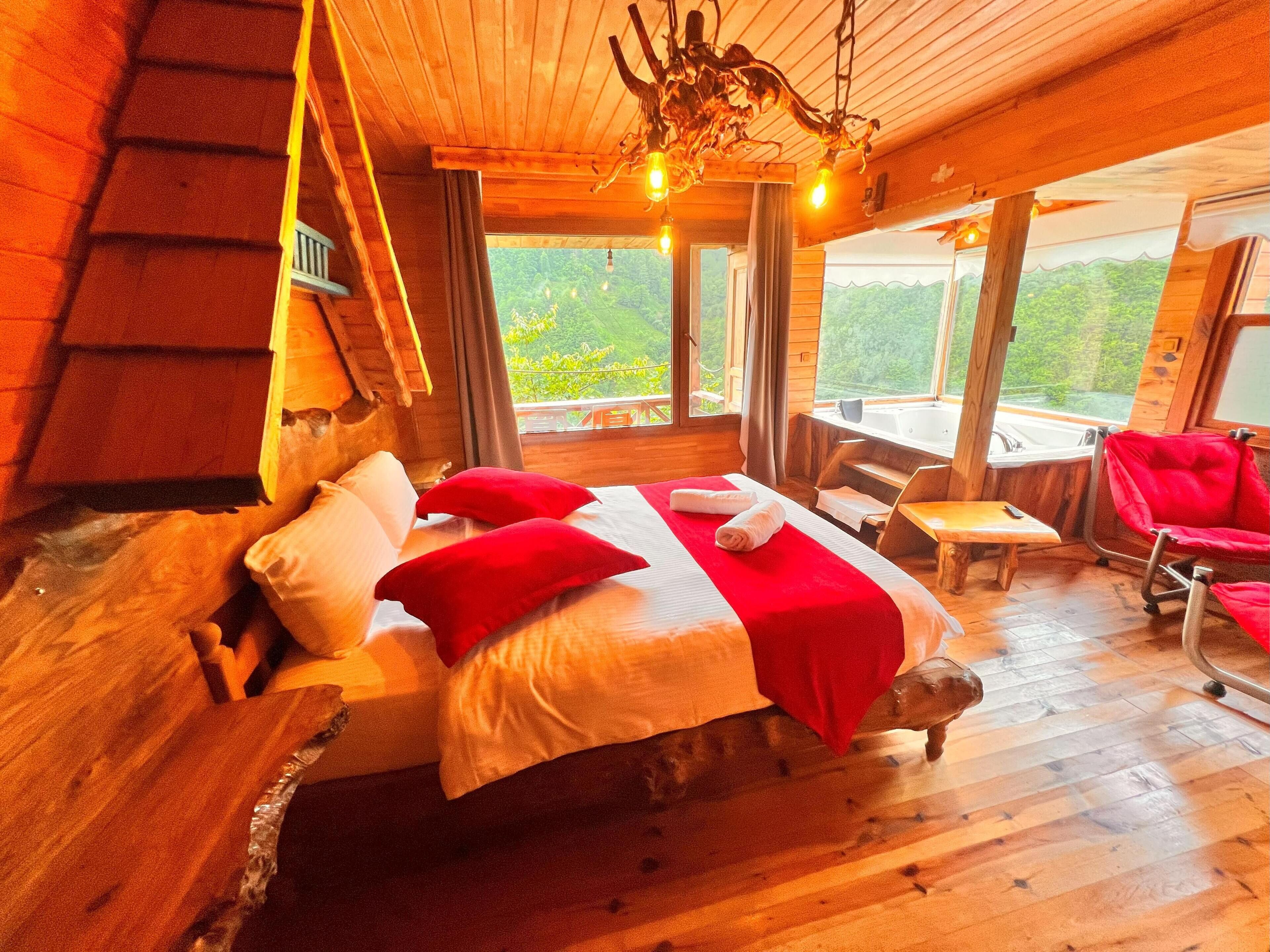 Une chambre dans une cabane en bois, avec un lit, un banc et une vue sur l’extérieur.