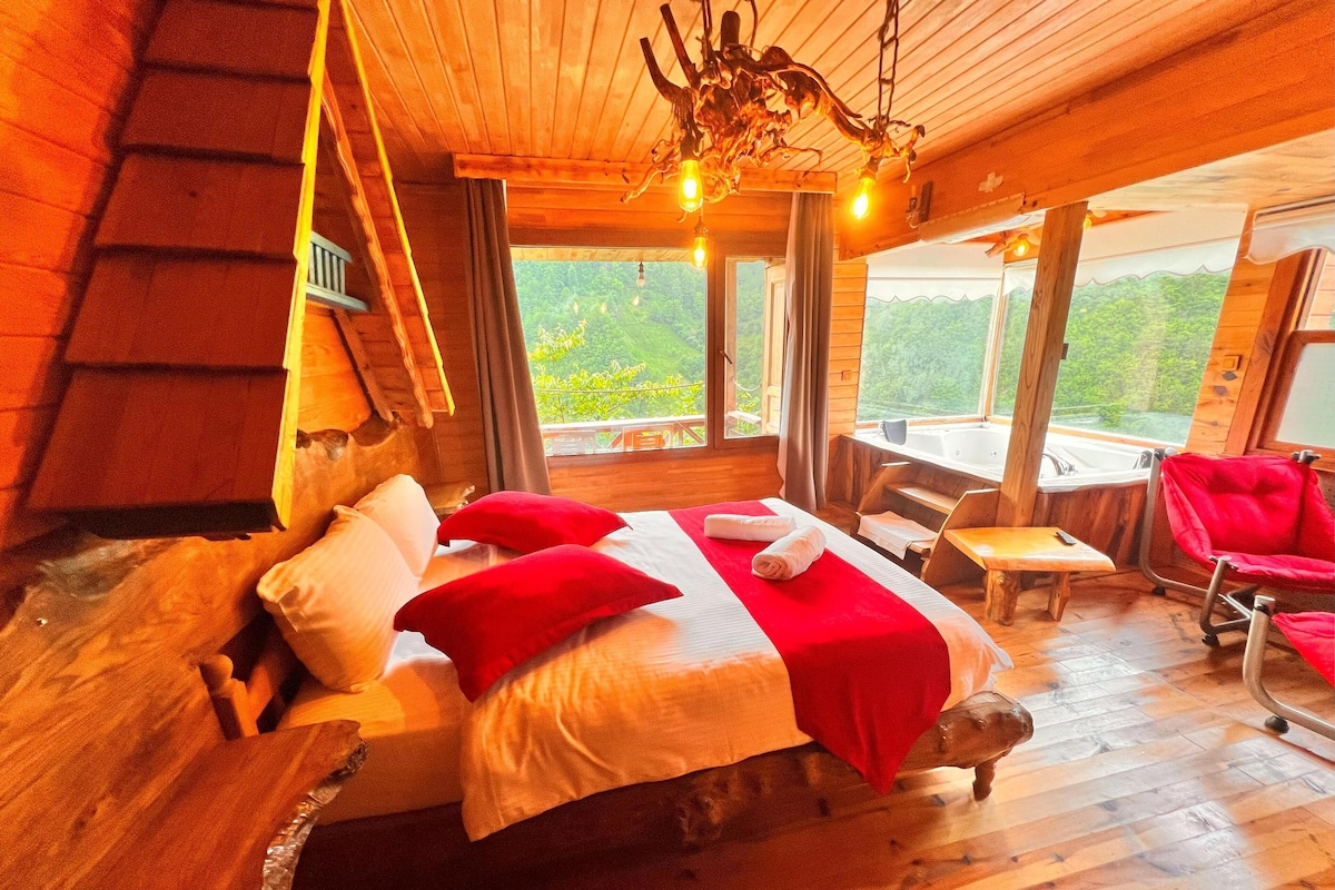 Un dormitorio de cabaña de madera con una cama, un banco y vistas al exterior.