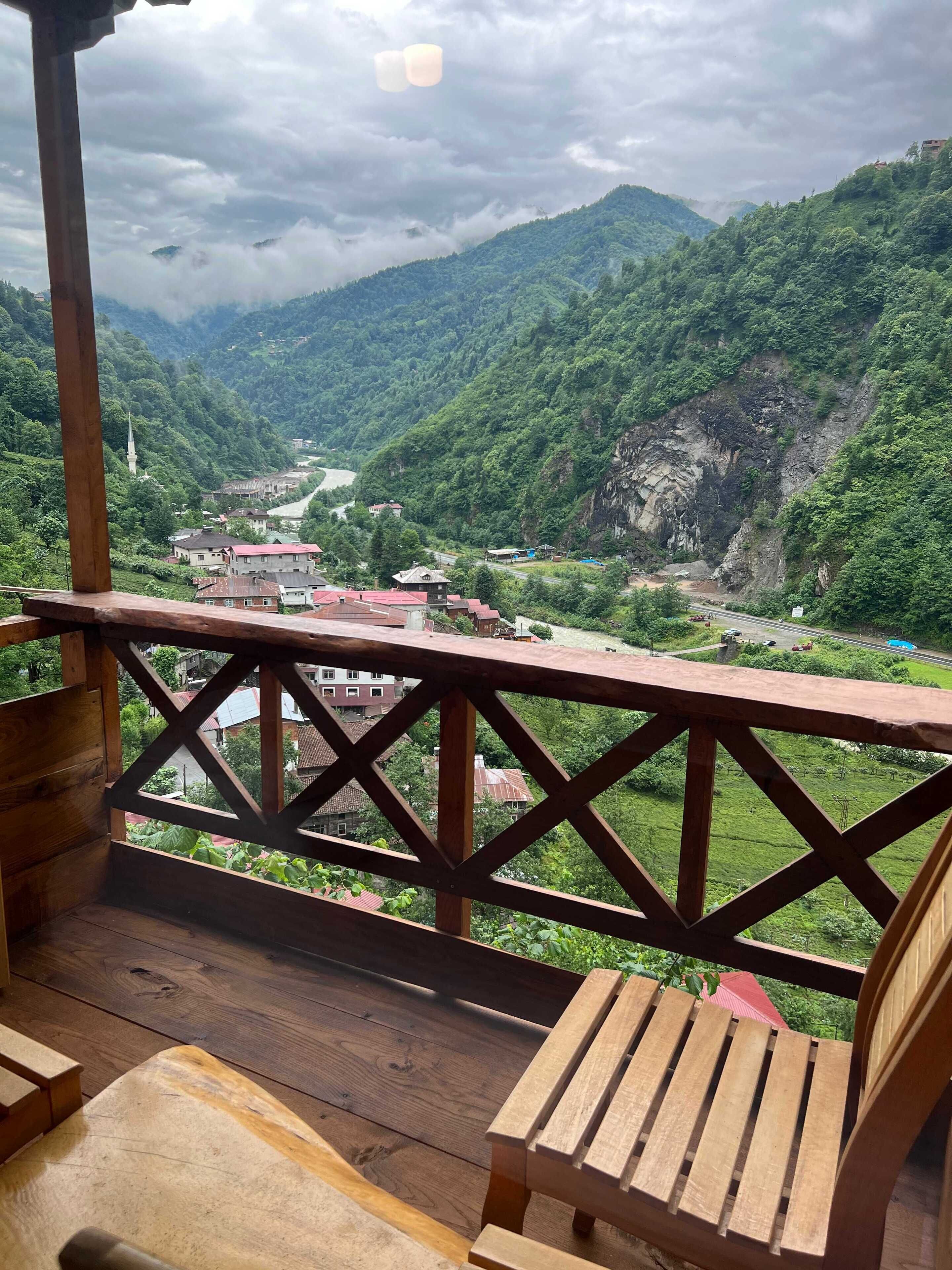 Un terrazzo in legno con vista su una valle e montagne.