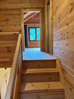 A wooden staircase leading to a second-floor room with a large window. - Panorama Bungalov Otel (Camlihemsin)