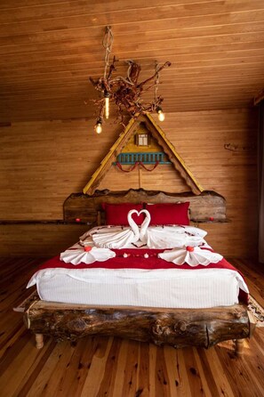 Ein gemütliches Schlafzimmer in einer Holzhütte mit einem Bett, einem einzigartigen Holz-Kopfteil und einem kleinen Fenster.