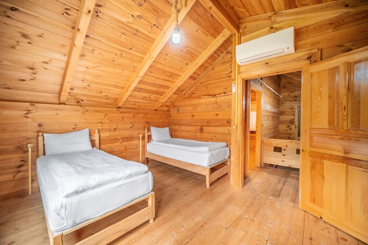 Une chambre de style cabane en bois, avec deux lits simples, un plafond en bois et une armoire intégrée.
