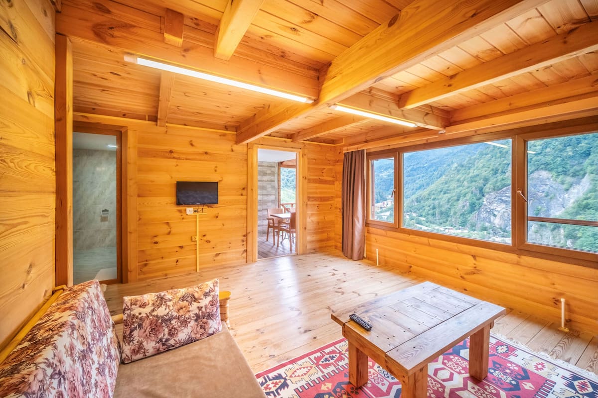 L'intérieur d'un chalet en bois, avec un canapé, une table et un téléviseur.