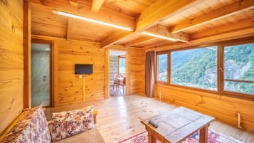 L'intérieur d'un chalet en bois, avec un canapé, une table et un téléviseur.