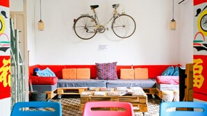 A room with a red sofa, a wooden coffee table, and a bicycle mounted on the wall. - Itinere Rooms - Hostel (Granada)