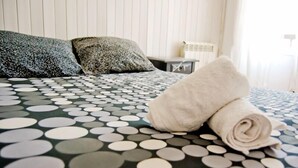 A neatly made bed with a polka dot bedspread, a rolled white towel, and two patterned pillows. - Itinere Rooms - Hostel (Granada)