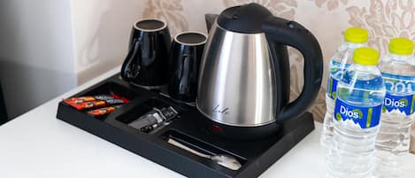 Eine Kaffeemaschine, zwei Tassen, ein Löffel und zwei Wasserflaschen auf einem Tablett.