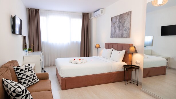 Une chambre d’hôtel avec un grand lit, un canapé, une table de chevet, une lampe et un téléviseur.
