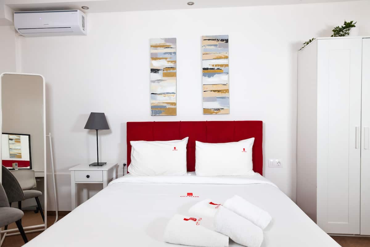 Een hotelkamer met een bed, een bureau, een stoel, een lamp en een kledingkast.