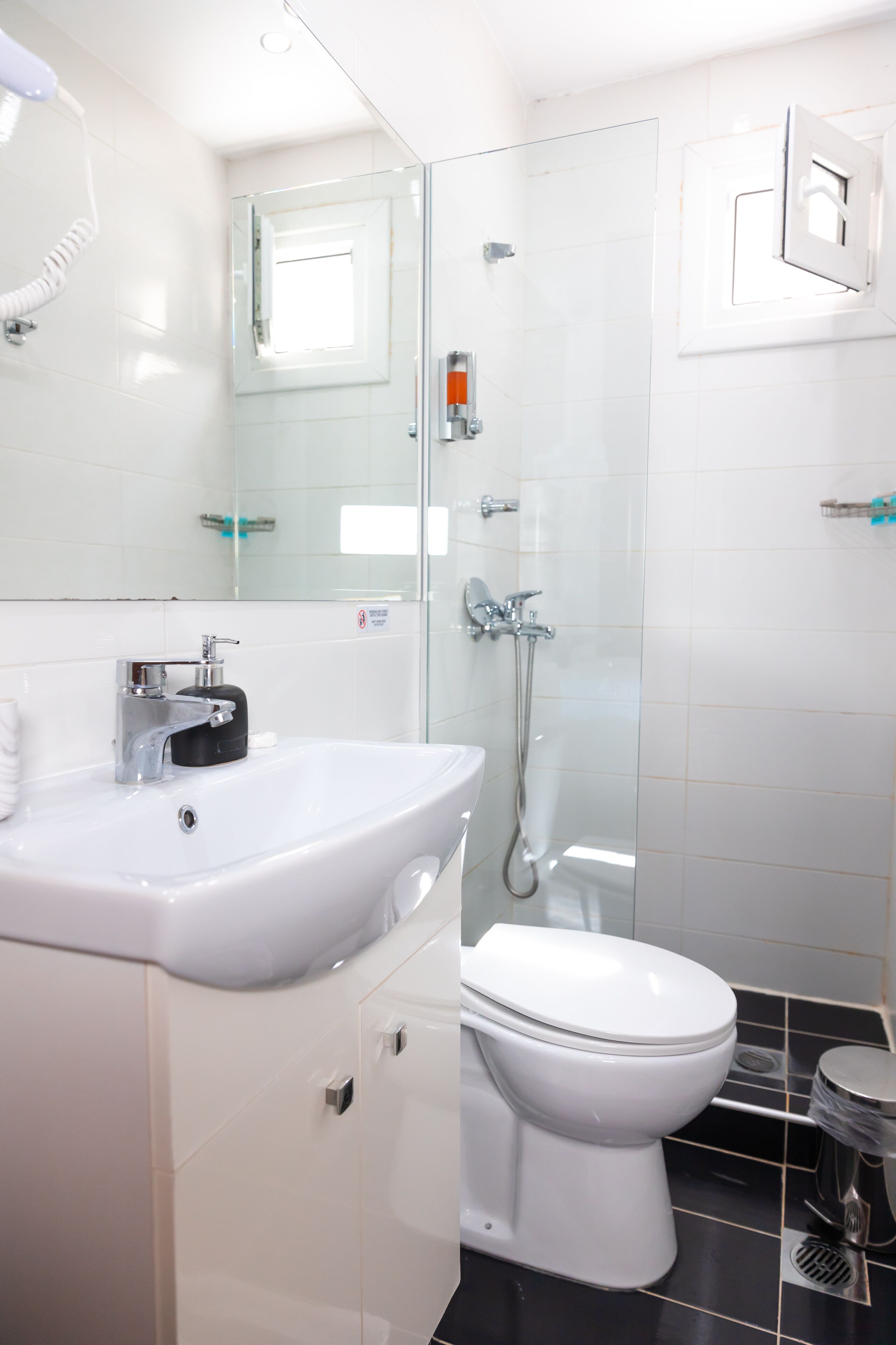 A modern bathroom with a white sink, toilet, and glass shower enclosure.