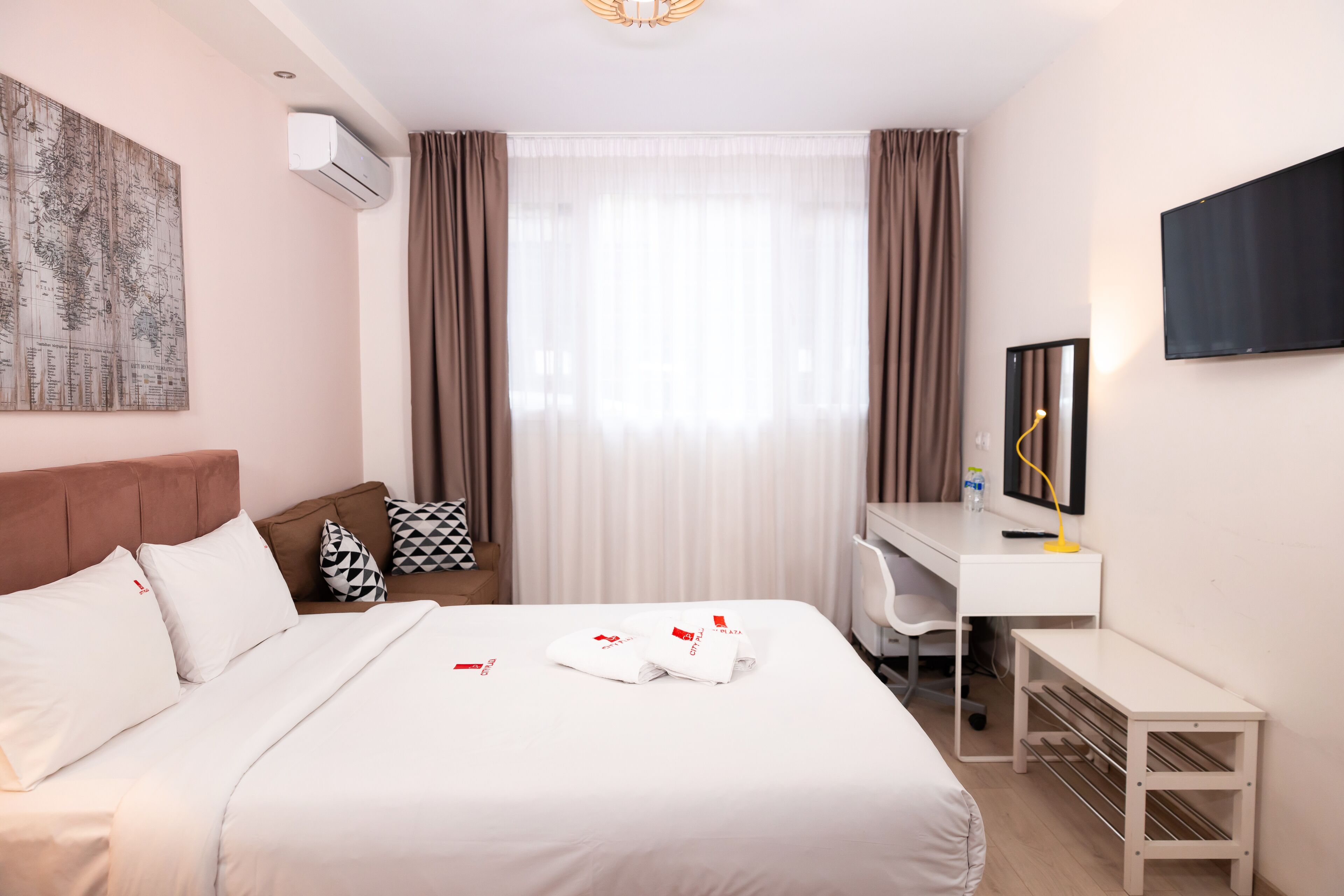 Een hotelkamer met een bed, een bureau, een stoel, een televisie en een kaart aan de muur.