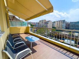 A balcony with a yellow awning, a small table, and two chairs.