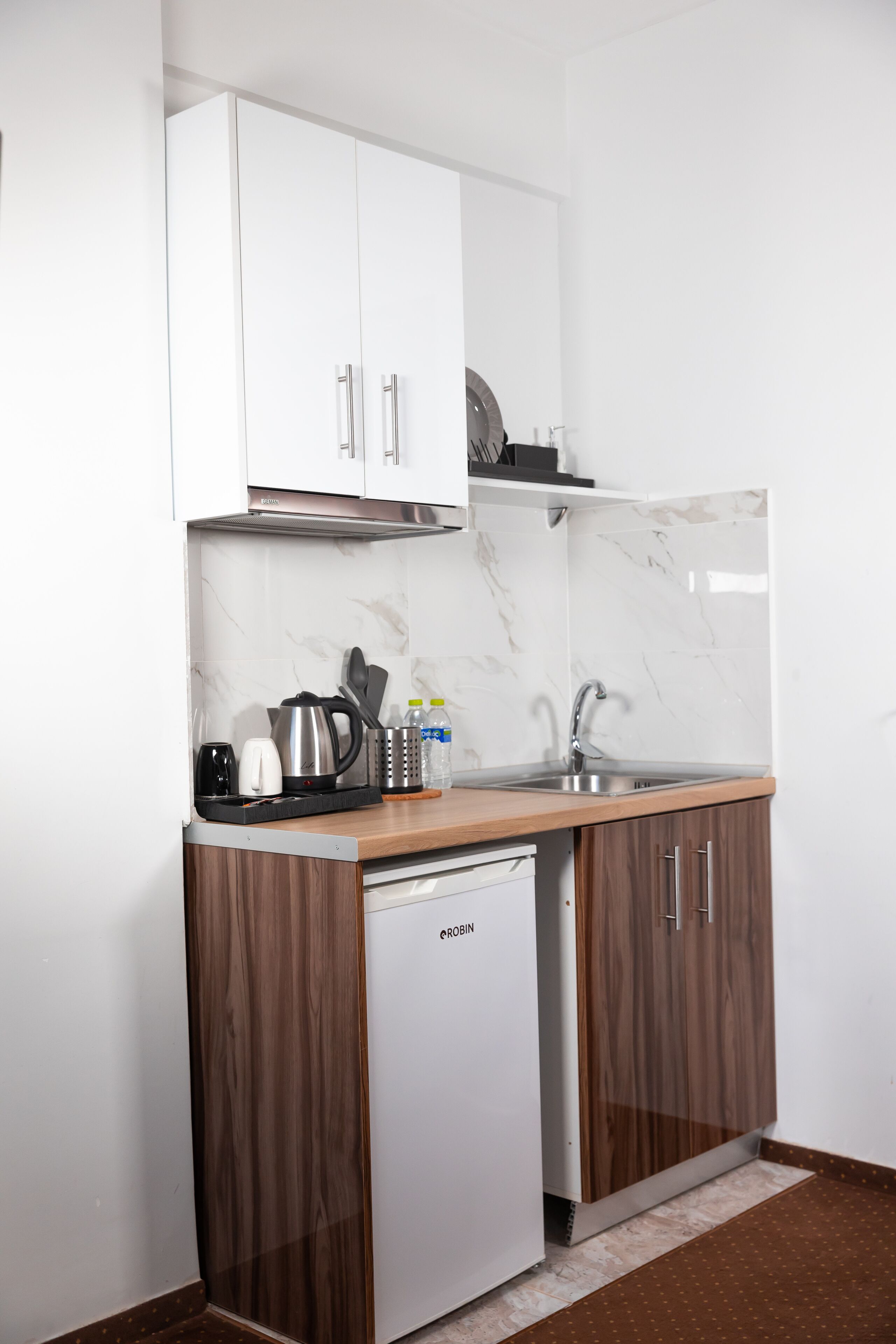 A compact kitchen with white cabinets, a stainless steel sink, and a built-in dishwasher.
