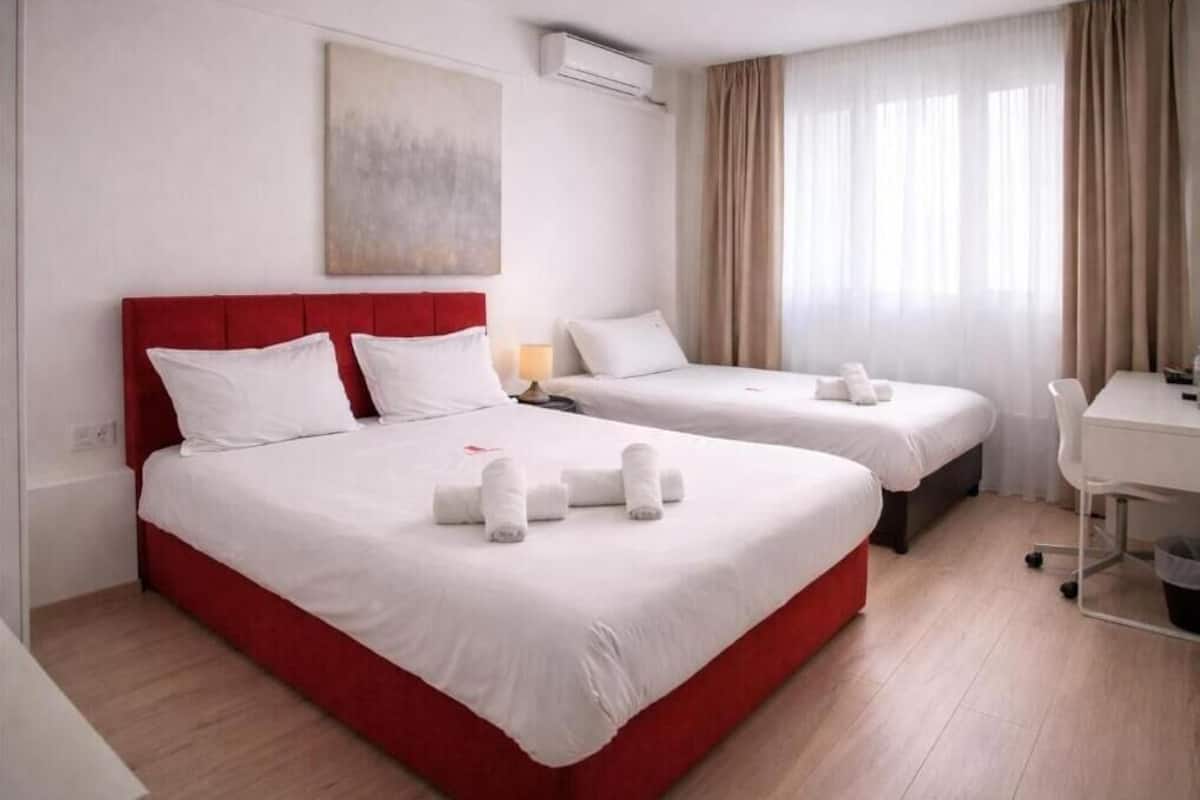 Een hotelkamer met twee bedden, een bureau en een stoel.