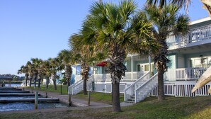 Een strandhotel met witte balkons, palmbomen en een trap naar de bovenverdiepingen.
