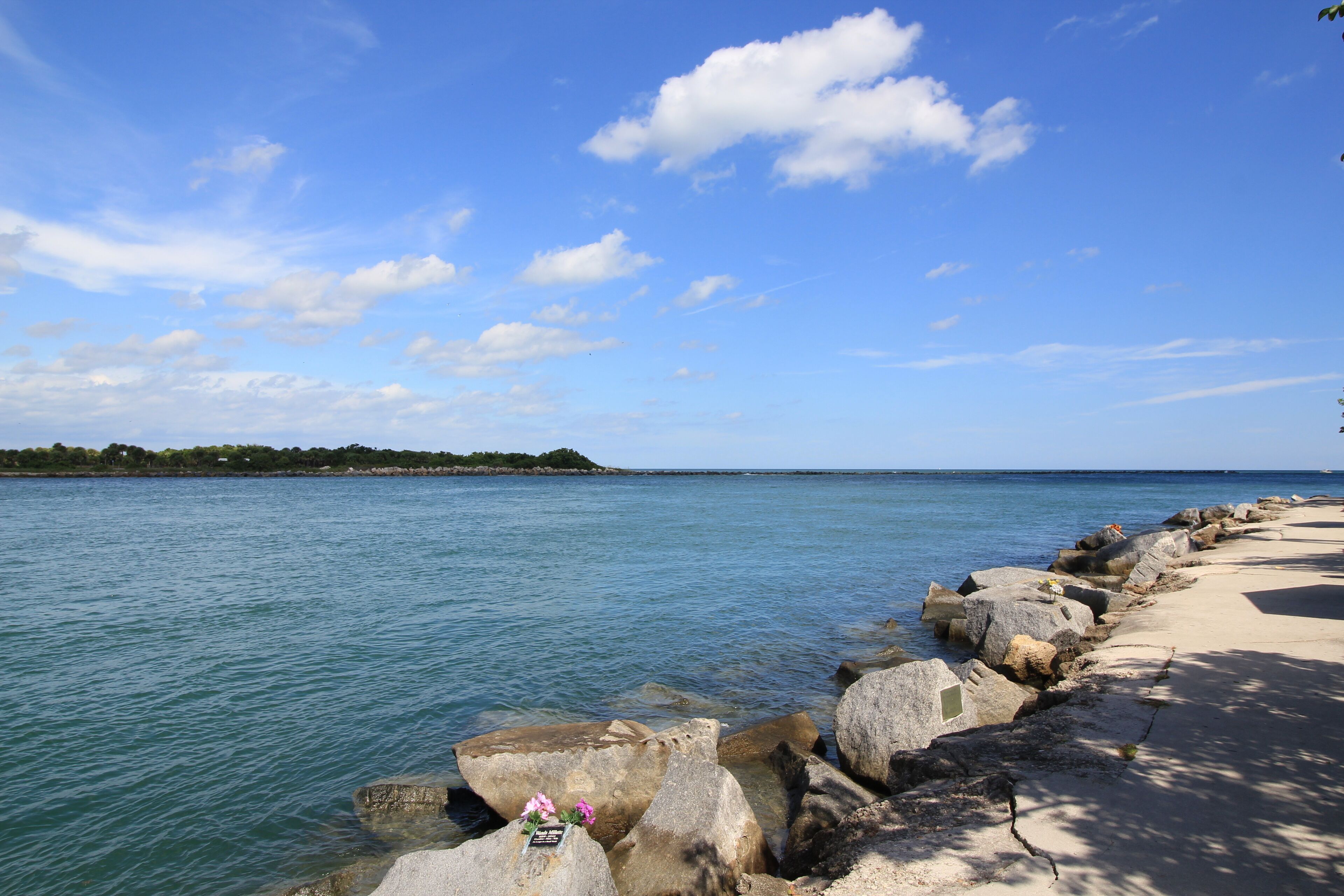 A coastal walkway with large rocks and a clear view of the sea.