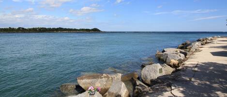 A coastal walkway with large rocks and a clear view of the sea.