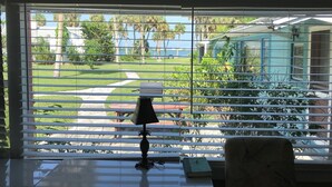 A room with a view of a well-maintained lawn, a pathway, and a distant building. - Mangrove Snapper Studio Cottage (Fort Pierce)