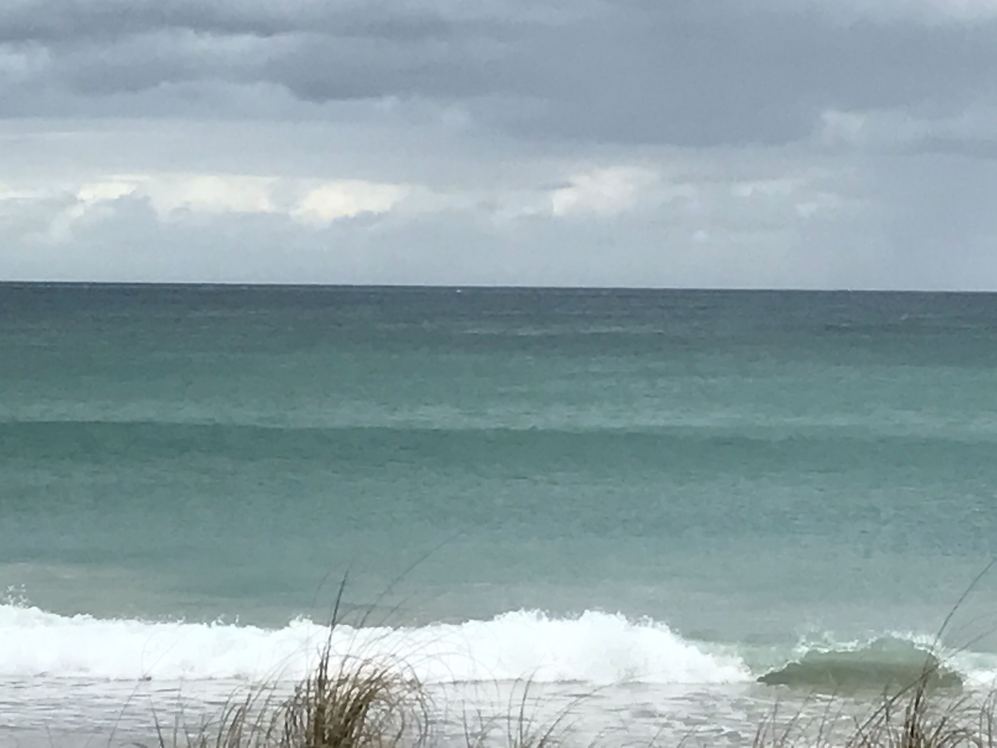 Una playa con olas y cielo nublado.