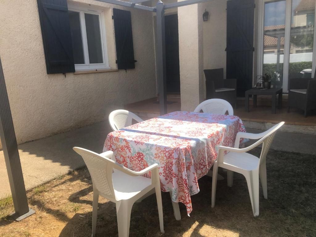 Une terrasse extérieure avec une table et des chaises, un espace abrité et une vue sur la rue.
