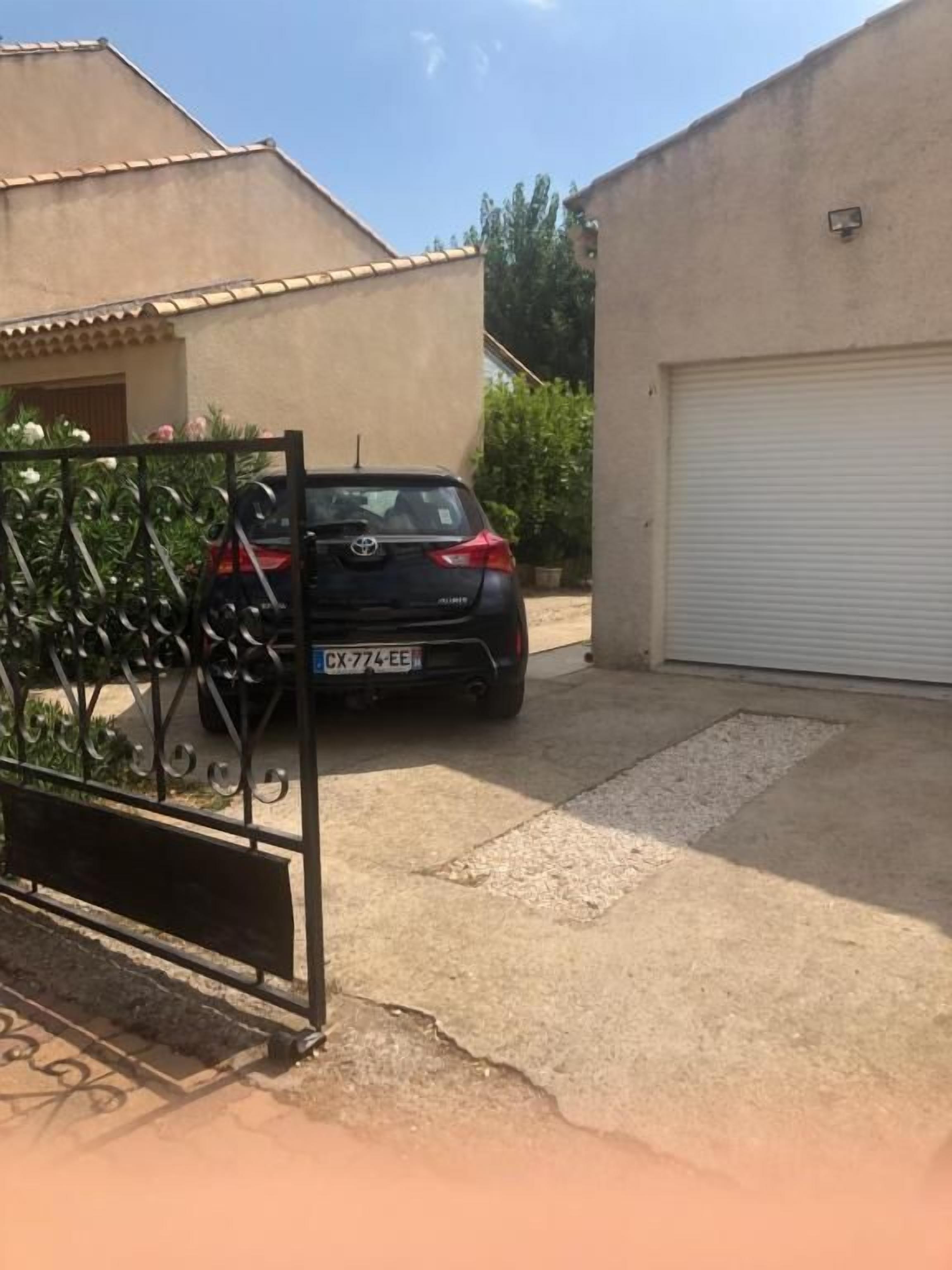 Un garage résidentiel avec une voiture garée à l’intérieur et la porte du garage fermée.