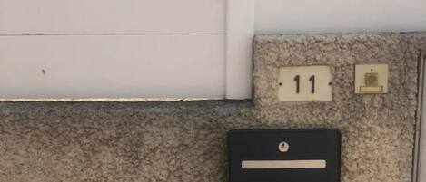 Fachada de edificio con cerca blanca, buzón y puerta con el número 11.
