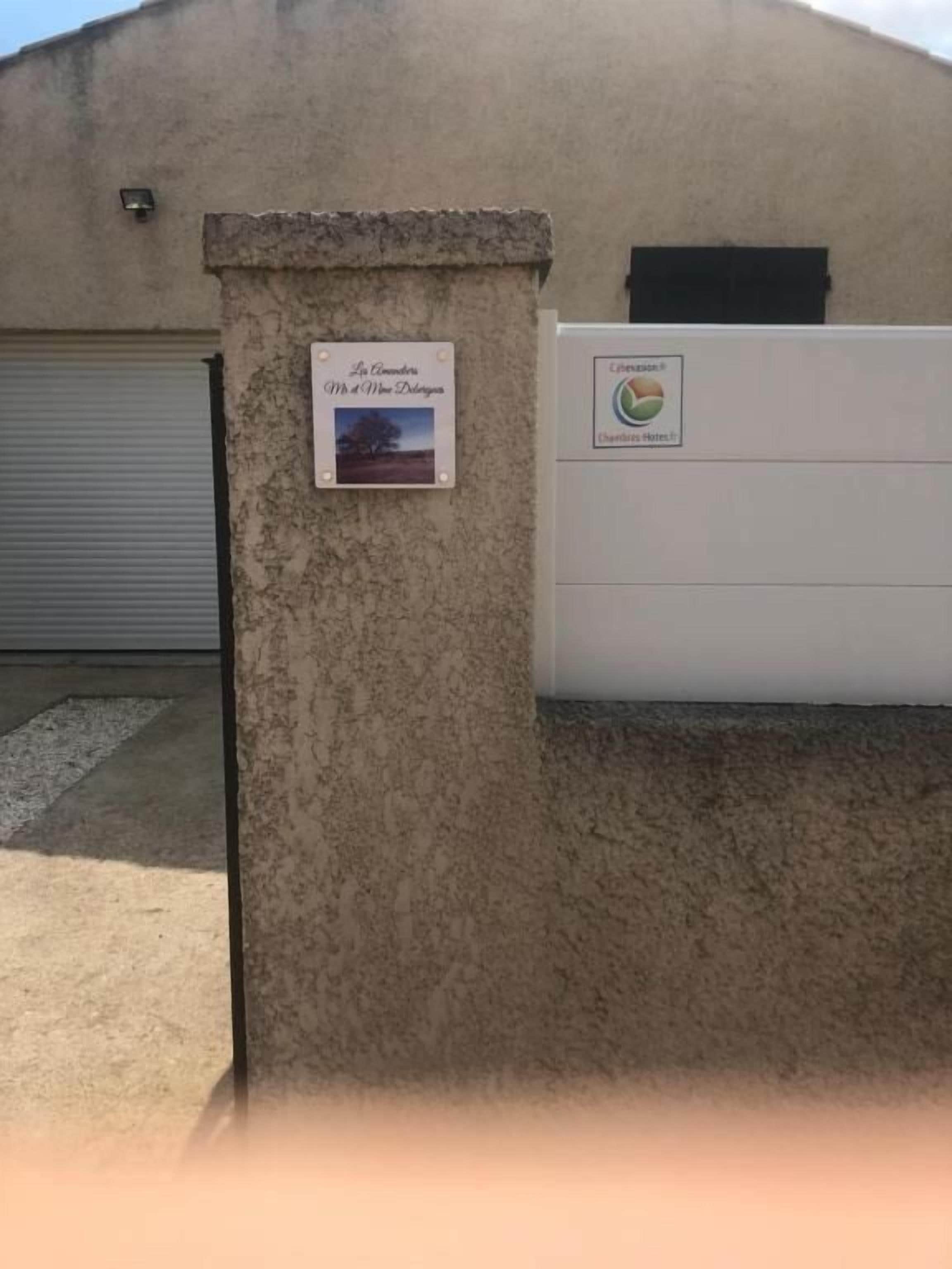 Un bâtiment doté d’un mur extérieur à la texture particulière, d’une porte de garage fermée et d’une enseigne représentant un paysage.