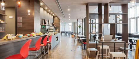 A modern cafe with a bar area, red bar stools, and a seating area with tables and chairs.