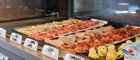 A deli counter with various meats and cheeses labeled for selection.