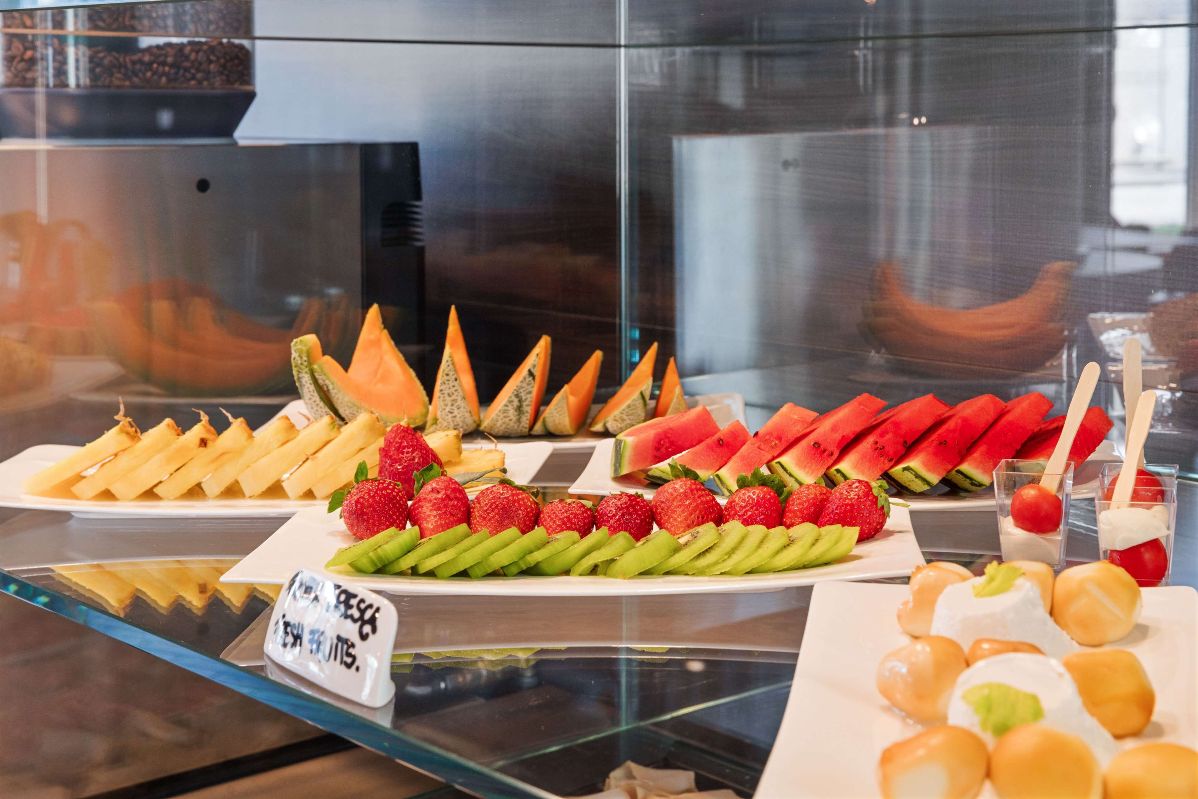 Variedad de frutas frescas y postres expuestos en una vitrina.