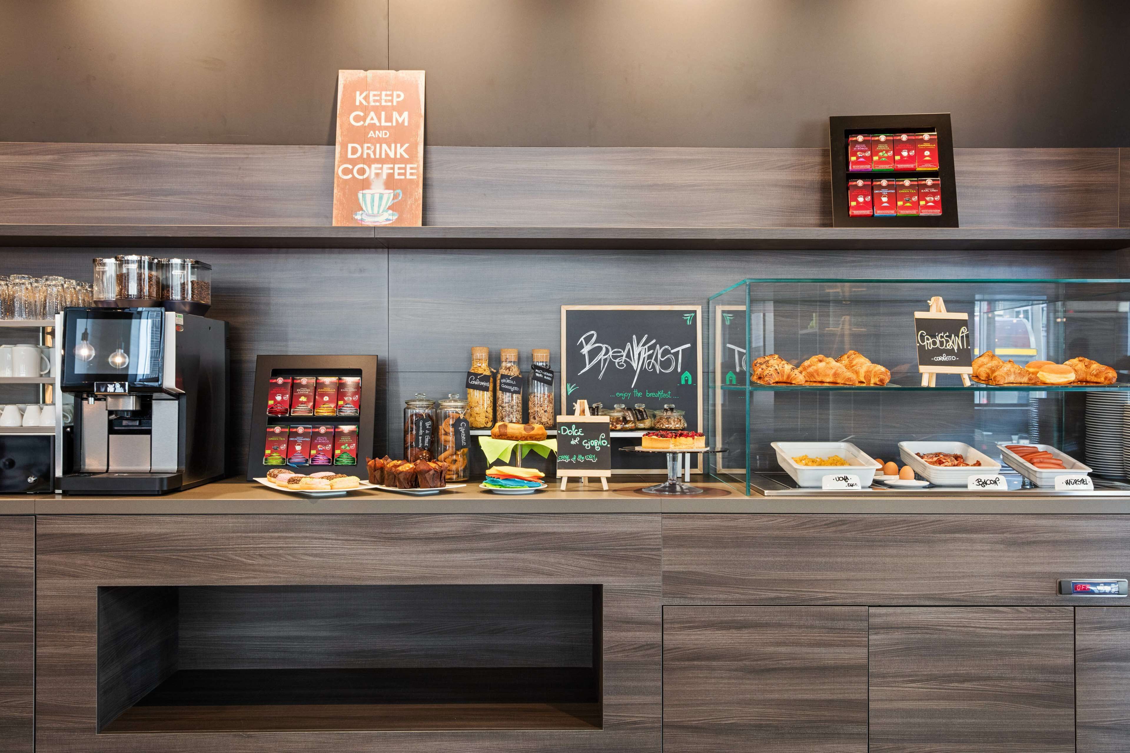 Una barra de desayuno con una máquina de café, frascos de condimentos y una variedad de pasteles y productos horneados.