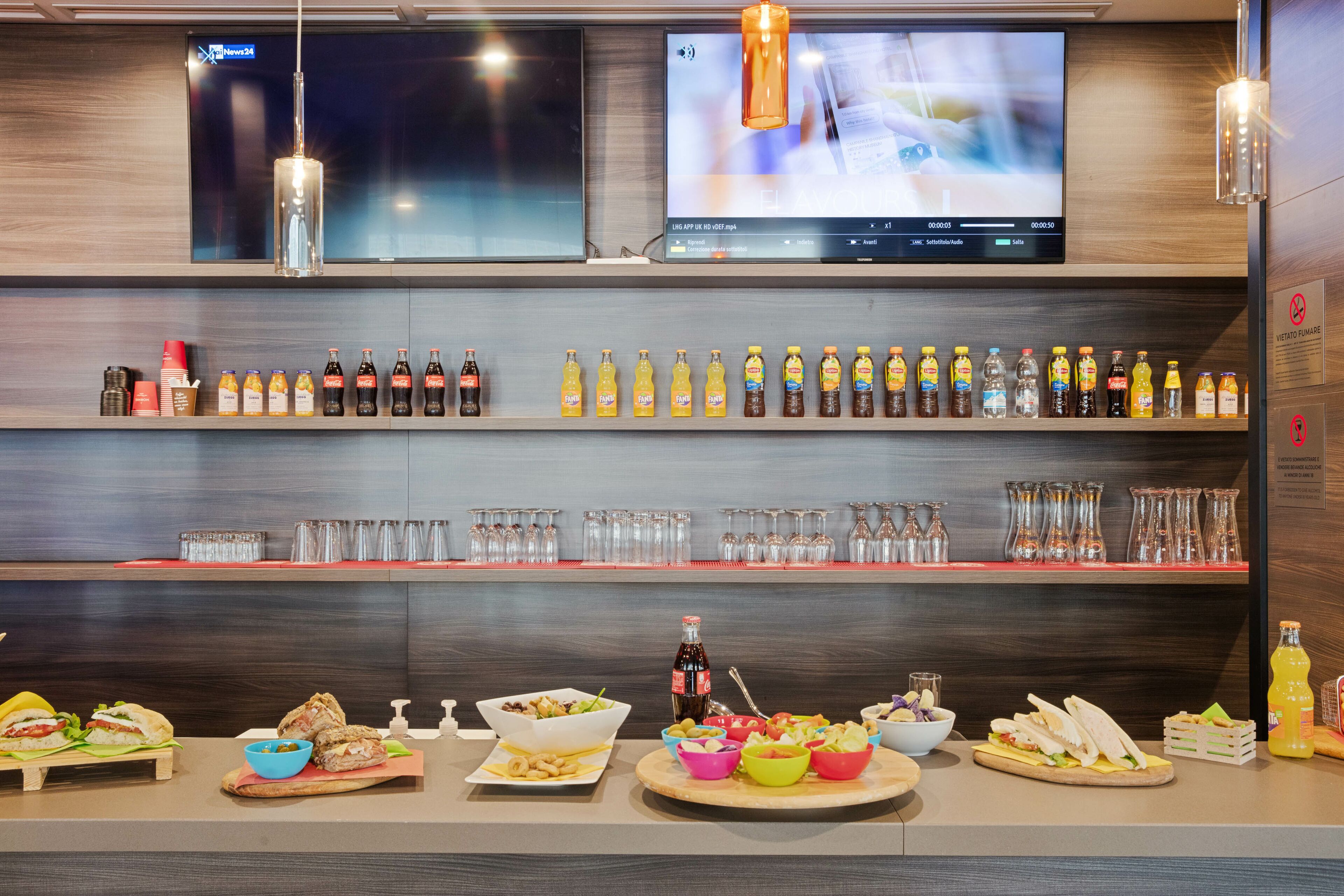 A bar area with a variety of beverages, glasses, and food items.