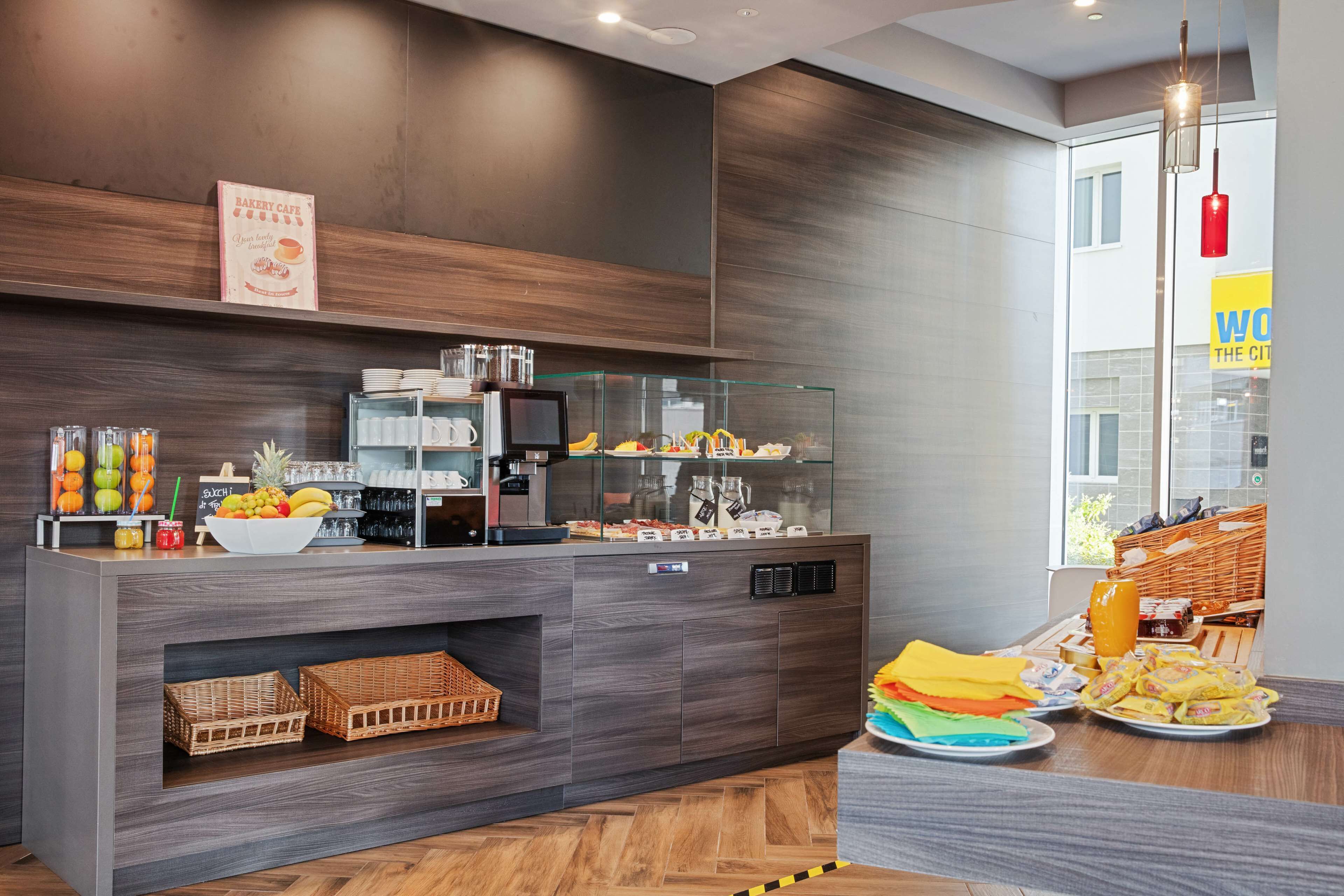 A modern breakfast bar with a coffee machine, fruit bowl, and various food items.