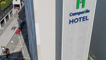 A modern hotel with a prominent sign, large windows, and a rooftop with solar panels.