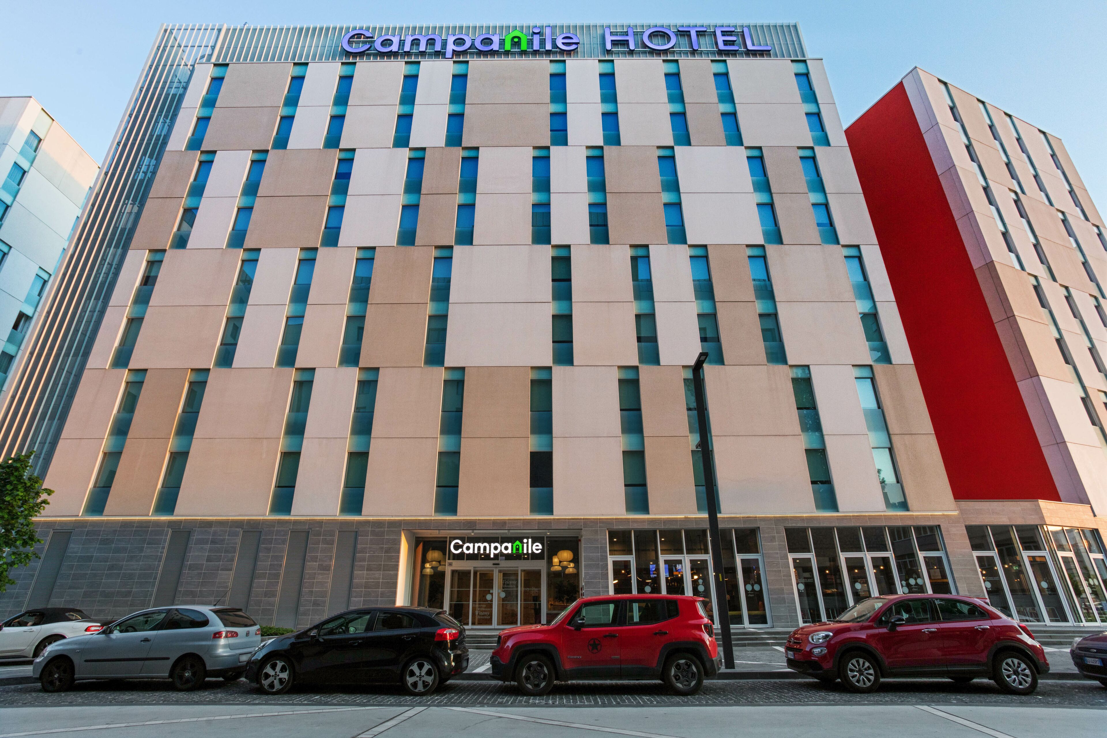 A hotel with a modern facade, large windows, and a prominent sign reading "Camparile HOTEL".